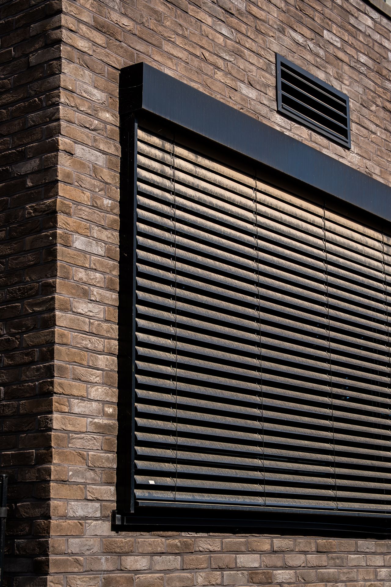 Buitenzonwering met rolluiken op een moderne gevel